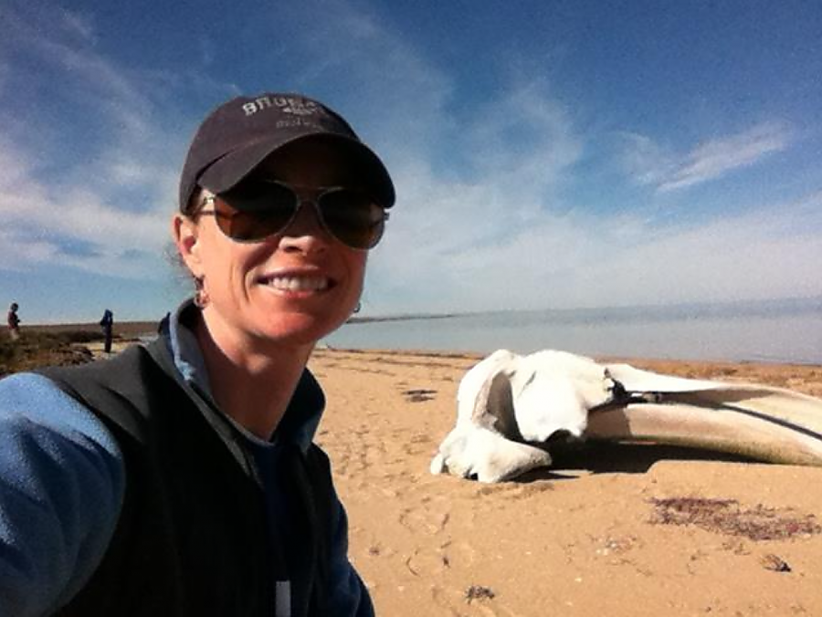 Cali Turner Tomaszewicz poses in front of a whale skull on a beach